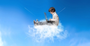 عکس با کیفیت کودک پسر در حال کار با لب تاپ نشسته بر روی ابرها و در آسمان مناسب مراکز آموزشی، مهدکودک و مدارس مجهز به فناوری ها و امکانات آموزش با ابزار دیجیتال
