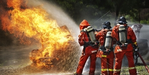 عکس با کیفیت آتش نشان های فداکار در حال خاموش کردن آتش درختان با شلنگ آتش نشانی و خاموش کردن آتش خودرویی در جنگل