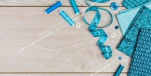 عکس با کیفیت پارچه ، متر ، نخ ها و دکمه های آبی و ابزار خیاطی روی میز چوبی