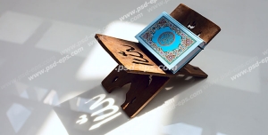 عکس با کیفیت نمایی از تابش آفتاب بر روی قرآن درون رحل با نقش کلمه الله بر روی رحل