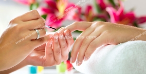 عکس با کیفیت آرایشگر در حال لاک زدن به دستان بانویی با زمینه گل در سالن زیبایی