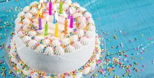 عکس با کیفیت کیک کوچک خامه ای تزئین شده با قیف و ماسوره و شمع و دانه های شکلات رنگی