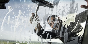 عکس با کیفیت شستشوی شیشه جلوی خودرو توسط کارگر کارواش