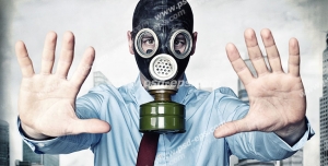 عکس با کیفیت مردی در شهری با هوای آلوده با ماسک شیمیایی در حال نشان دادن علامت Stop با دستانش