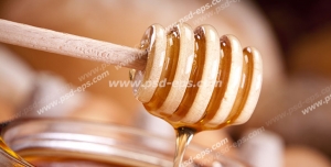 عکس با کیفیت برداشتن عسل از درون شیشه آن با قاشق مخصوص عسل از روی میز صبحانه