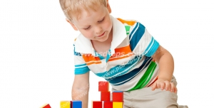 عکس با کیفیت پسر بچه در حال بازی با آجرهای بازی رنگارنک و اسباب بازی