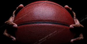 عکس با کیفیت تبلیغاتی توپ بسکتبال بین دو دست در تاریکی