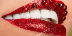 عکس با کیفیت تبلیغاتی نگین های براق بر روی لب زن با رژ قرمز و دندان های سفید و درخشان