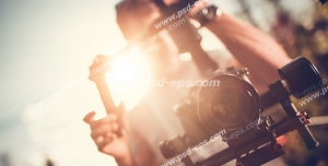 عکس با کیفیت تبلیغاتی مرد در حال فیلم برداری با دوربین حرفه ای و تابیده شدن نور خورشید از پشت سر فیلم بردار