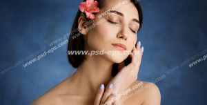 عکس با کیفیت تبلیغاتی زن با چشمای بسته شده و گل زیبا بر روی موهای کوتاه او و بک گراند سرمه ای